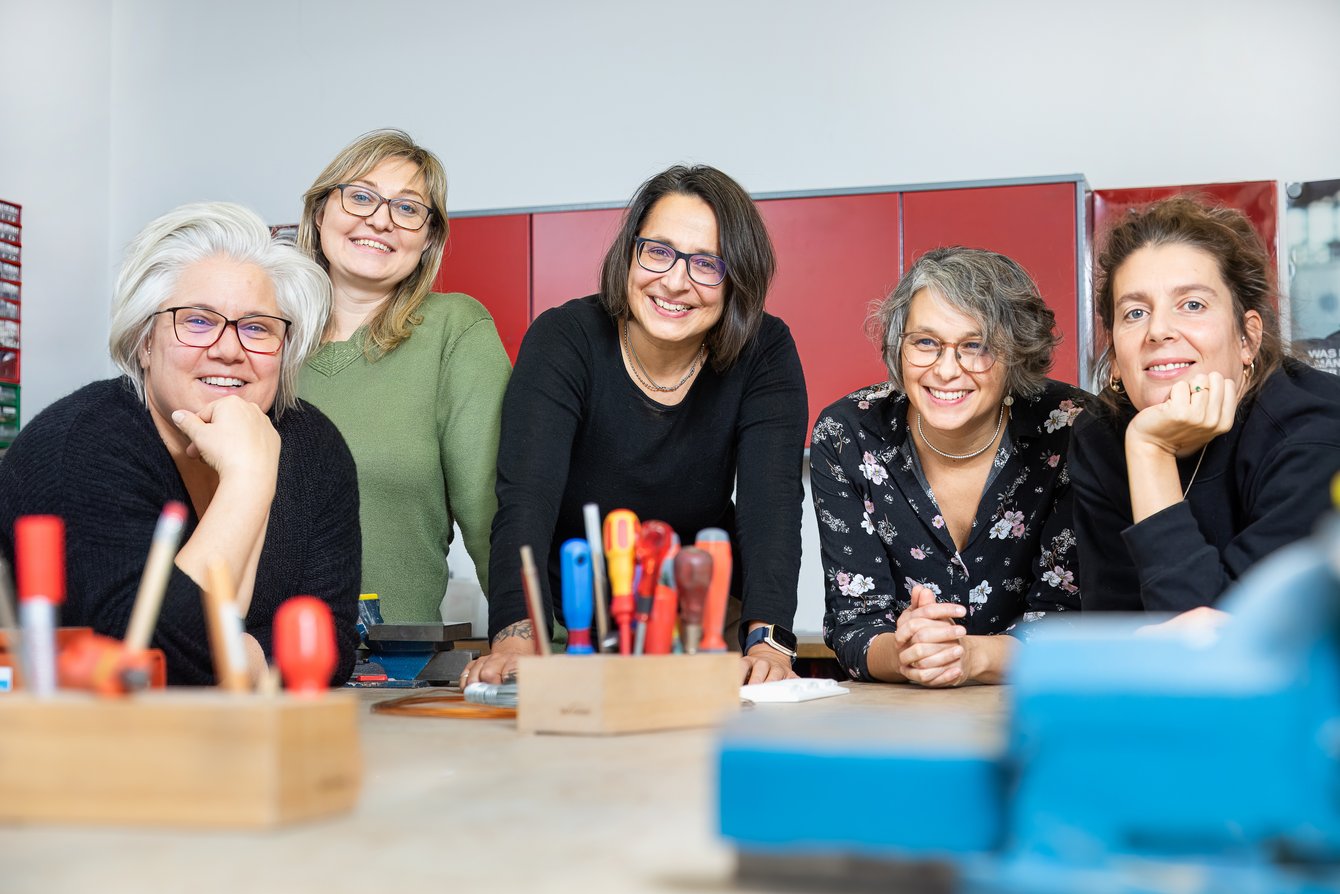 Die Berater:innen von youngFIT stehen nebeneinander in der Werkstatt und lächeln direkt in die Kamera.